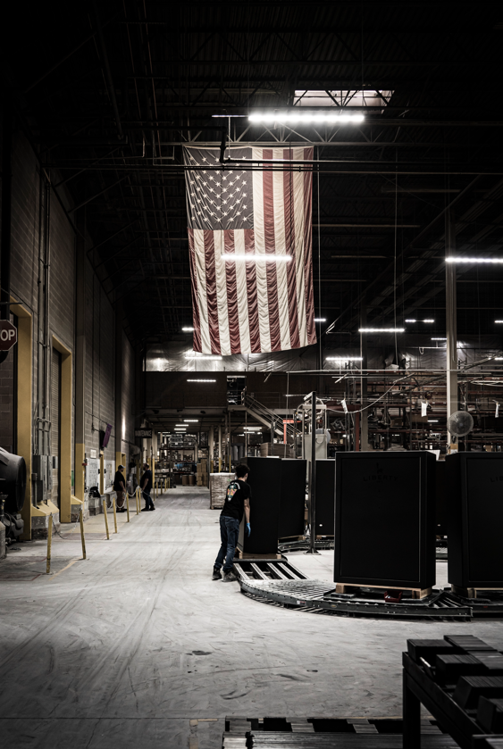 Liberty Safe manufacturing facility with gun safes on the production line beneath a large American flag - made in the USA